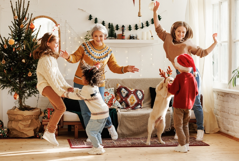 A beautiful, happy family dancing around the living room with their Golden Retriever puppy on Christmas day to celebrate the holiday. 